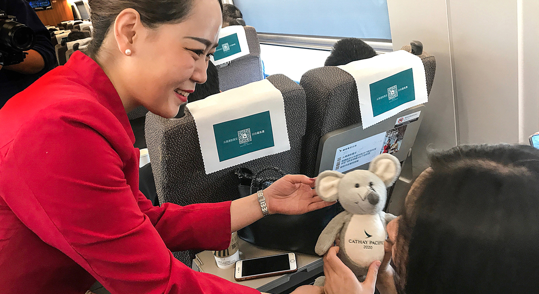 国泰空服员在高铁专列上向乘客赠送国泰航空鼠年玩偶。