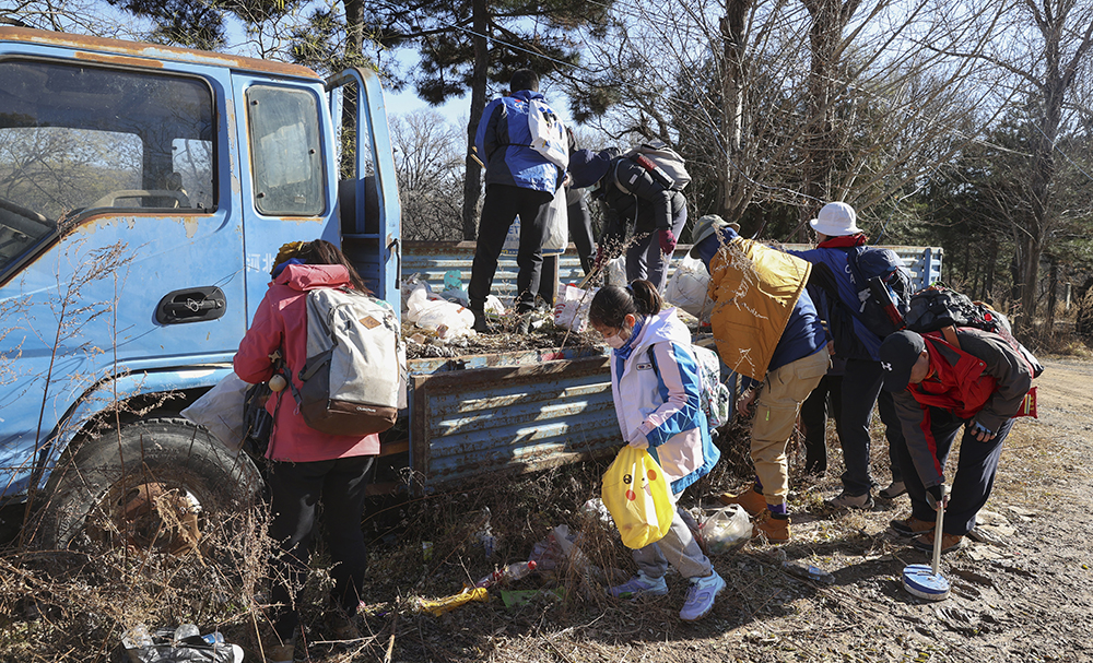 爱心大使们在京西古道一辆废弃卡车上清理垃圾，还大自然以清洁“无痕”。
